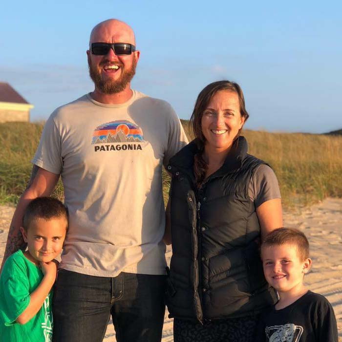 A smiling family of four stands on a sandy beach, dreaming of future renovations & remodels.