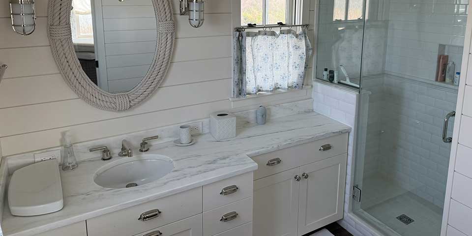 Bright bathroom with white vanity, oval mirror, and glass shower—perfect for renovations & remodels.