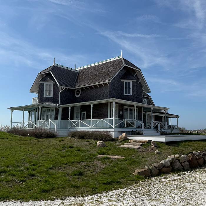 Victorian-style house with wraparound porch and new window & door replacement on a grassy lawn.