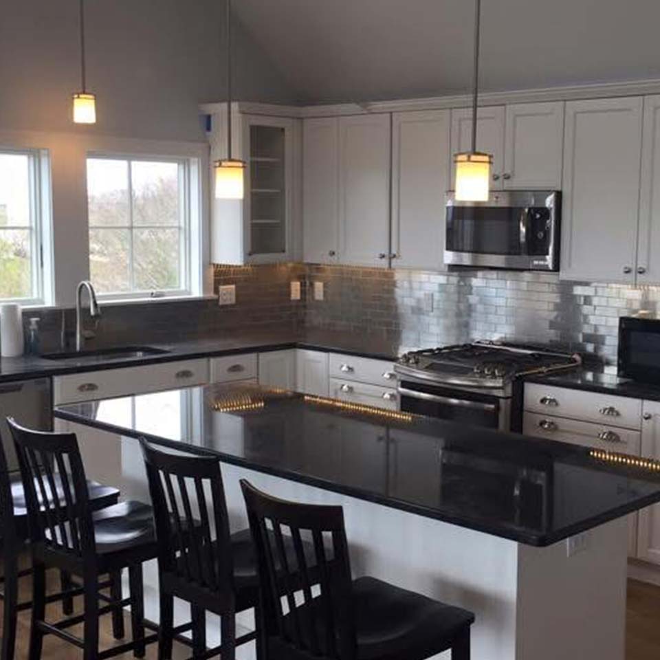 Modern kitchen with black countertops, white cabinets—perfect for Kitchen & Bath Remodels.