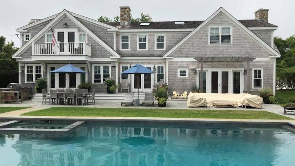 Large gray house with deck, blue umbrellas, pool, and recent window & door replacement.