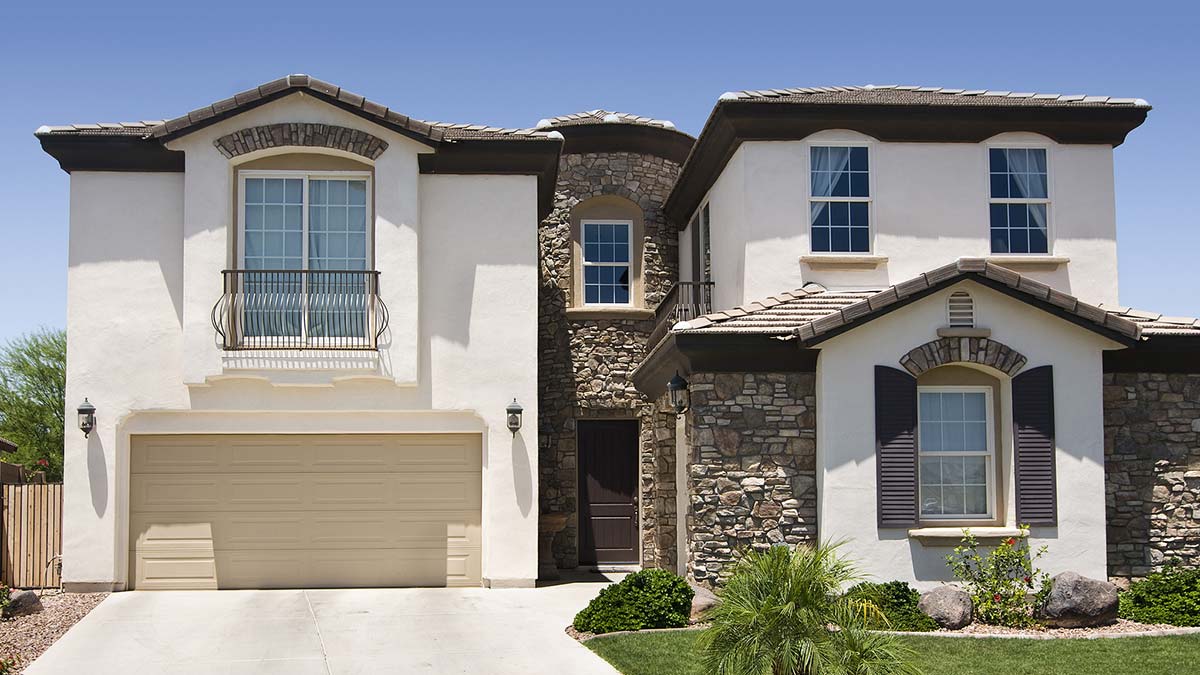 Two-story suburban house with stone accents, tan stucco, double garage, and new window replacement.