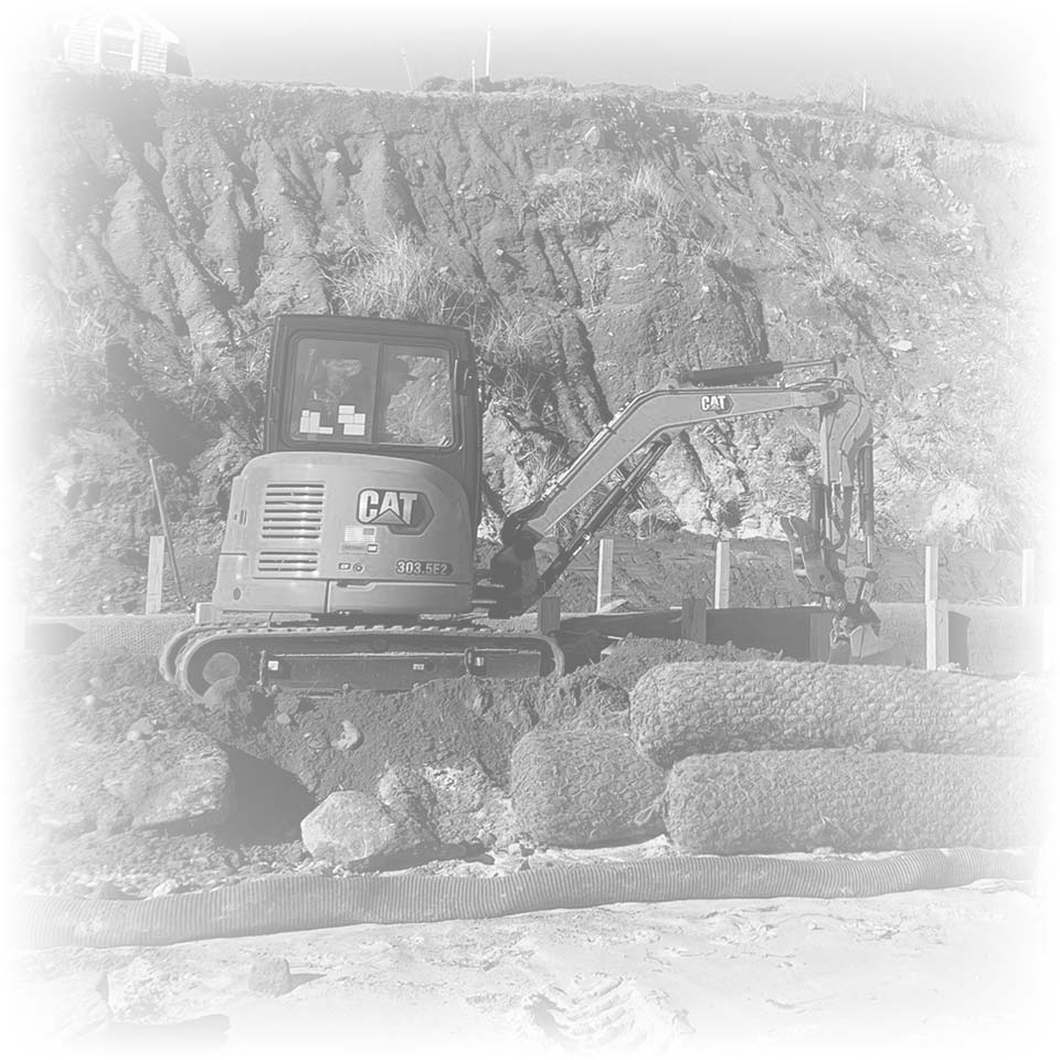 A small CAT excavator preps the rocky slope for Foundation to Finish custom home building.